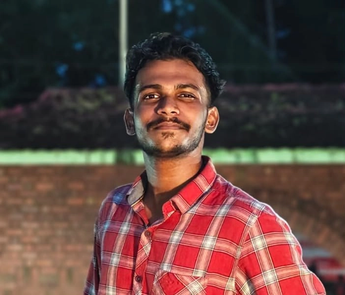 ALT Text: Best freelance digital marketing expert in Palakkad – portrait of a man wearing a red checkered shirt outdoors at night.